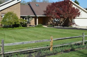 wooden fence in front of residential home with freshly cut grass