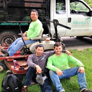 Allentuck Landscaping team leaning on a lawn mower
