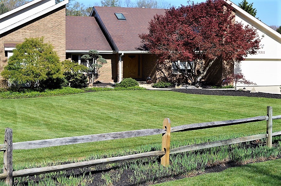 wooden fence in front of residential home with freshly cut grass