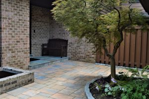 front entryway of brick residential home with brown bench and a tree
