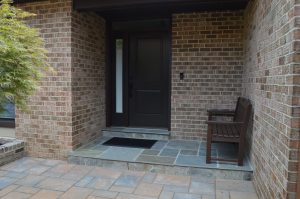 front entryway of brick residential home with brown bench