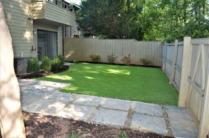 white wooden fence with freshly cut grass and paver walkway