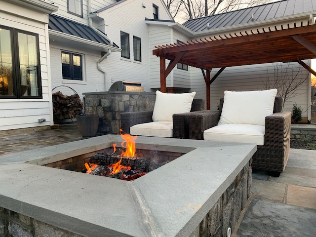 outdoor patio with stonework fire pit and patio chairs