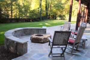A beautiful stone patio with seating and a firepit.