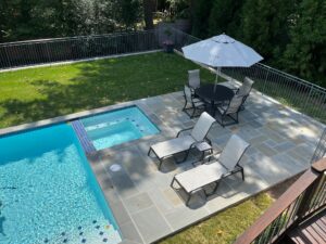 An aerial view of a pool area in the backyard of a home with lush landscaping.