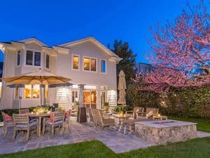 elegant flagstone patio fireplace behind a multistory residential home at dusk