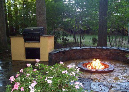outdoor kitchen with lit fire pit and half circle stone seating Allentuck Landscaping Rockville, MD